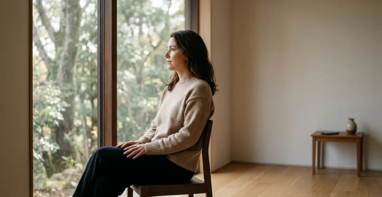 Portrait d'une femme tournant le dos à son smartphone posé loin d'elle, contemplant par la fenêtre un paysage naturel apaisant dans une lumière dorée