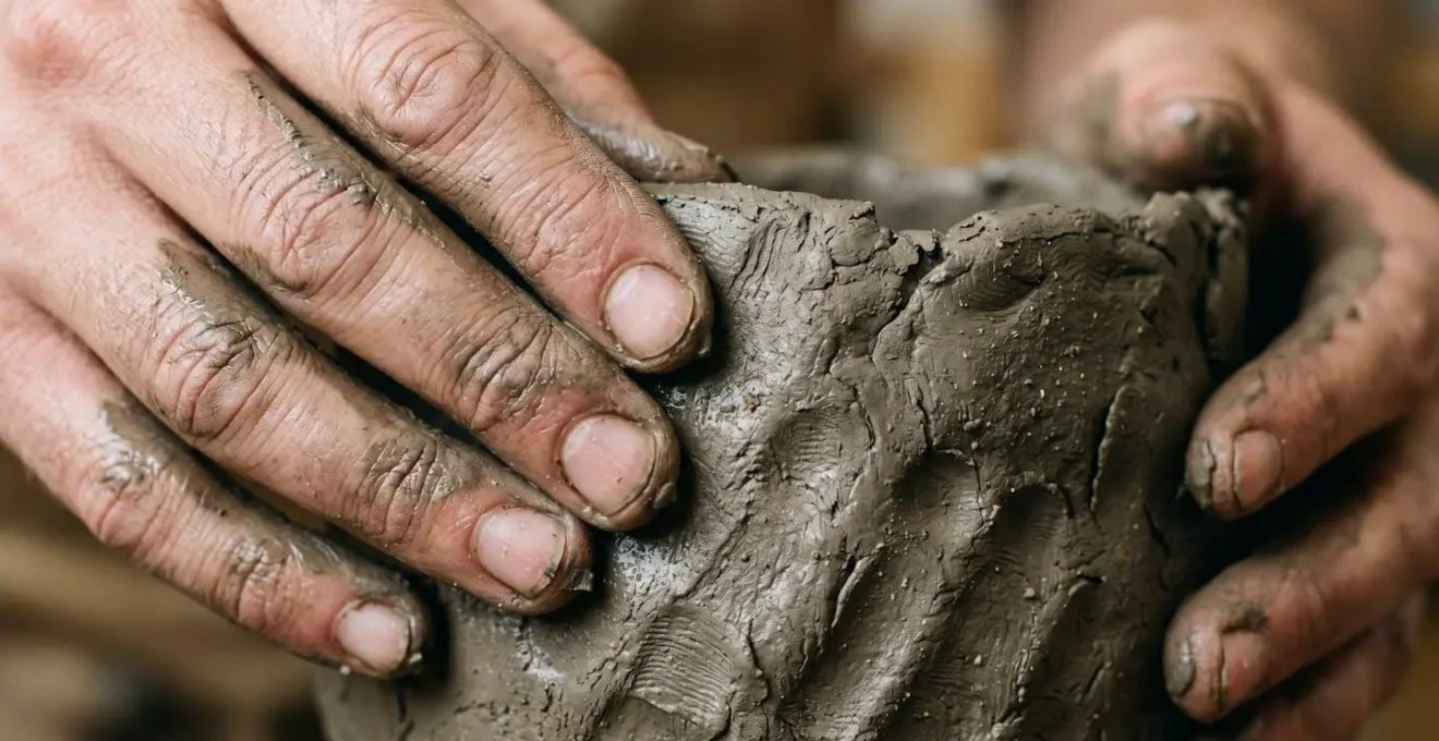 Gros plan sur des mains modelant l'argile avec des traces et imperfections visibles